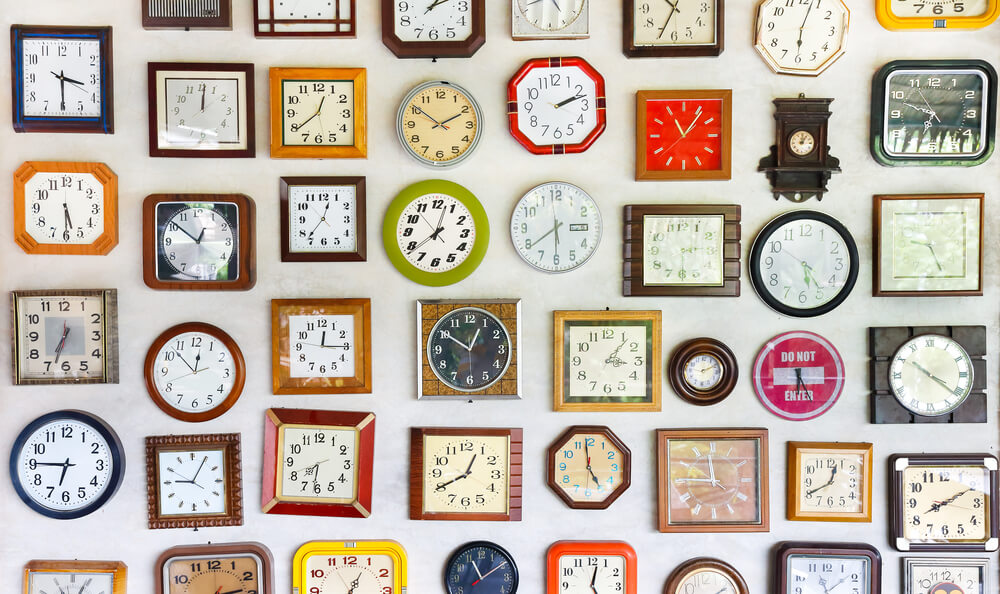 Vários relógios diferentes pendurados em uma parede.